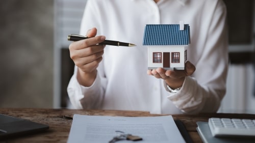 contract on table with woman holding miniature house